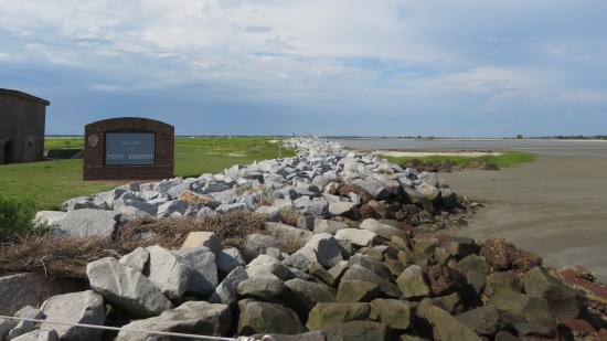 Welcome to Fort Sumter sign in front of piled rocks lining the shore.