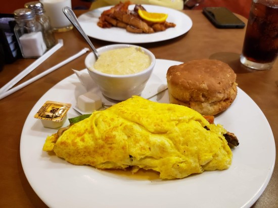 Omelet with a cup of cheesy grits and a biscuit.