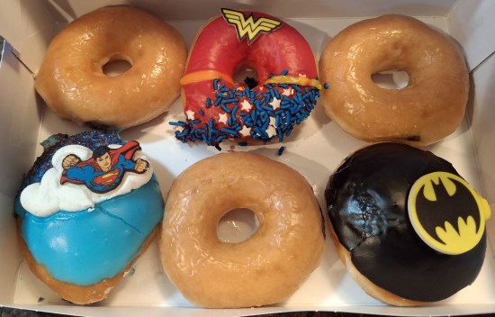 A box of six Krispy Kreme donuts, three of them plain. The others are iced to resemble Superman, Batman and Wonder Woman.