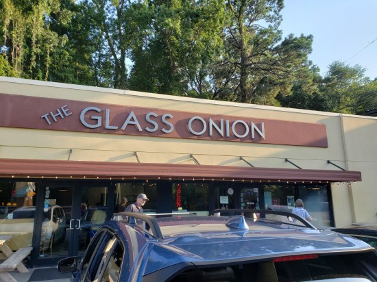Strip-mall restaurant called The Glass Onion with tall South Carolina trees behind it.