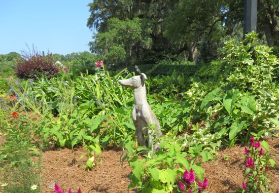 Garden with a stone dog statue shaped a lot like the Simpsons' bedraggled greyhound.