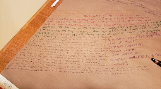 "Birdhouse in Your Soul" lyrics written diagonally on brown-bag paper on a restaurant table.