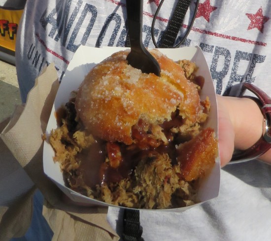 Anne holding a fried biscuit sandwich with pulled pork and apple barbecue sauce.