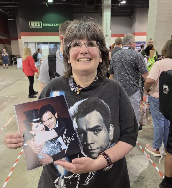 Anne beaming with her autographed Obi-Wan photo while wearing an old shirt with the Padawan Kenobi's face on it.