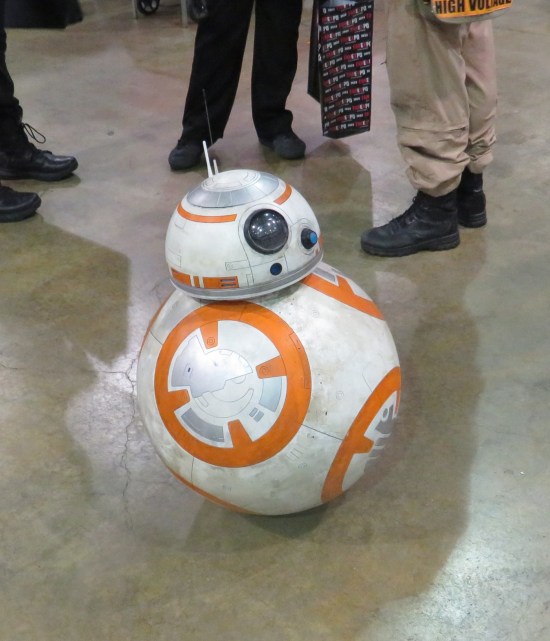 Remote-control tiny BB-8 next to several human feet.