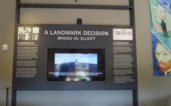 Educational kiosk entitled "A Landmark Decision" about the case in the caption. Paragraphs are written on the wall around a TV showing old news footage.