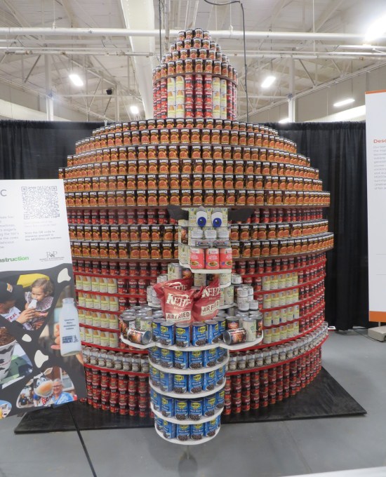 canned food sculpture of Dairy Barn and cow statue in front of it.