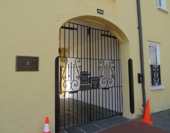 Gated arched doorway on a yellow building with a sign confirming it's a Charleston-Hamburg Railroad landmark.