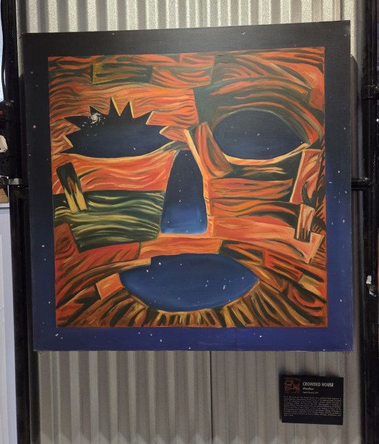 Square face made of wood, with blank ellipses for eyes and mouth.