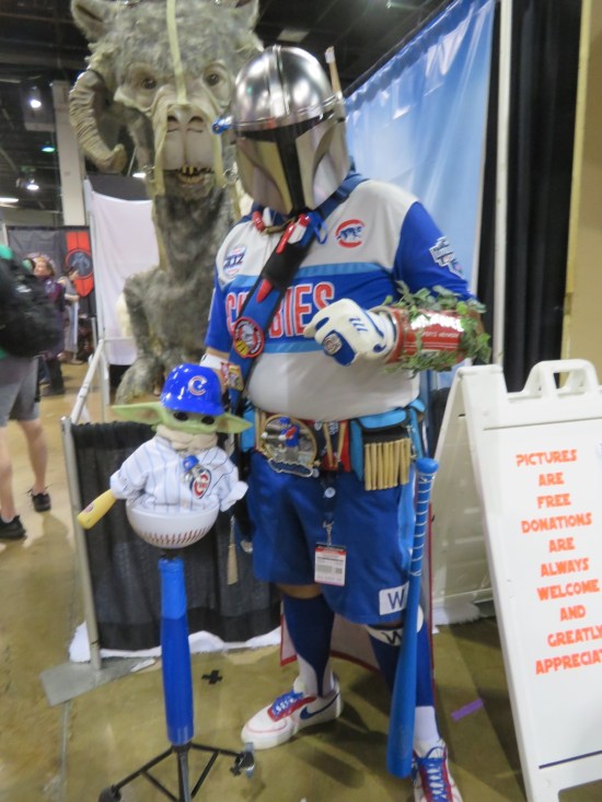 Chicago Cubs superfan with a Mandalorian helmet and a Grogu doll dressed like a Cubs player.