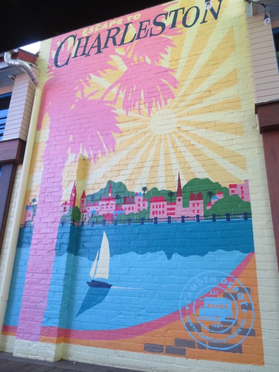 Pastel painted mural titled "Escape to Charleston" with pic of sailboat in Charleston Harbor and big pink palm tree silhouette in foreground.