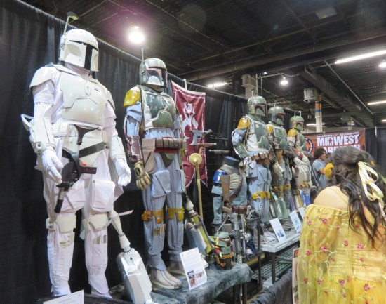Multiple Boba Ferr suits standing in a row on display, plus one all-white Mandalorian armor.