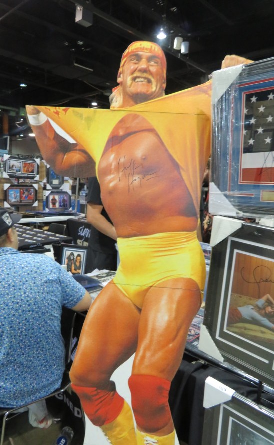 Autographed Hulk Hogan standee, him dressed all in yellow and tearing off his shirt.