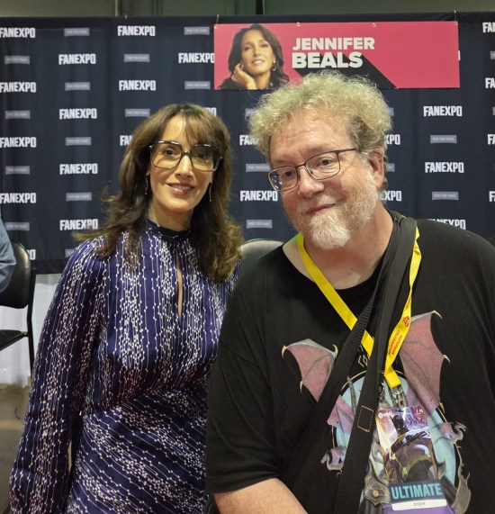 Me posing like a normal person with Jennifer Beals, who has glasses and a purple dress.