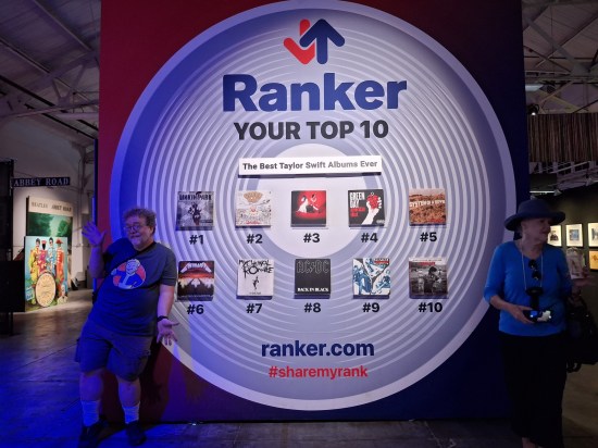 Me doing jazz hands next to cover replicas for Hybrid Theory, Dookie, Elephant, American Idiot, Toxicity, Master of Puppets, The Black Parade, Back in Black, Social Distortion's 1990 self-titled major-label debut, and Scarecrow.