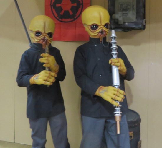 Two cosplayers as the Mos Eisley Cantina band from the original Star Wars, each with space instrument.