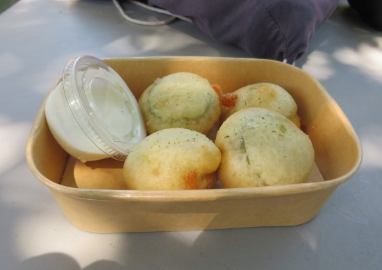Four fried blobs with pickles and cookies in each of them, served in a bowl with a cup of Ranch dressing.