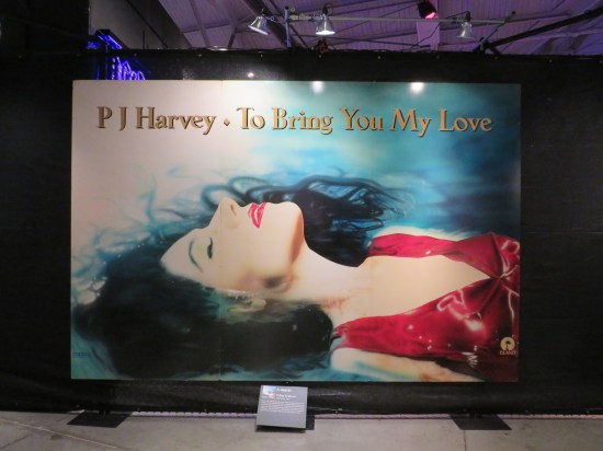 Double-sized pic of PJ Harvey lying under album title in a red dress.