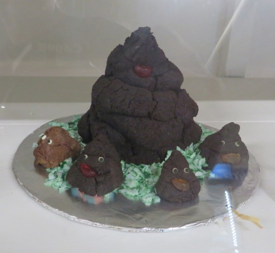 Five cakes in all: four tiny ones shaped like poo emojis, all surrounding a much larger Queen Poo Emoji.