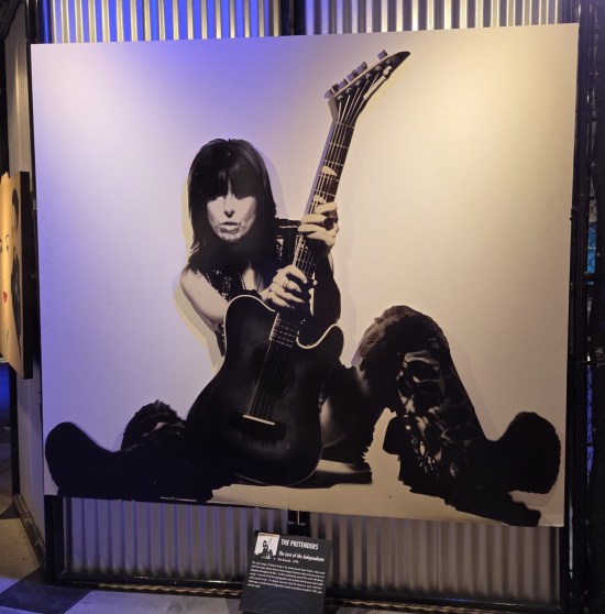 Black-and-white pic of Chrissie Hynde sitting behind a guitar.