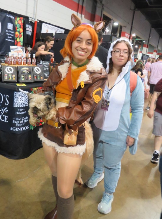 Squirrel Girl cosplayer carrying a very cute doggo and a human friend.