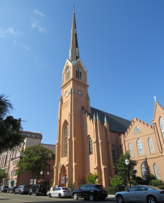 Brown and beige Gothic Revival church on large street with extremely tall steeple.