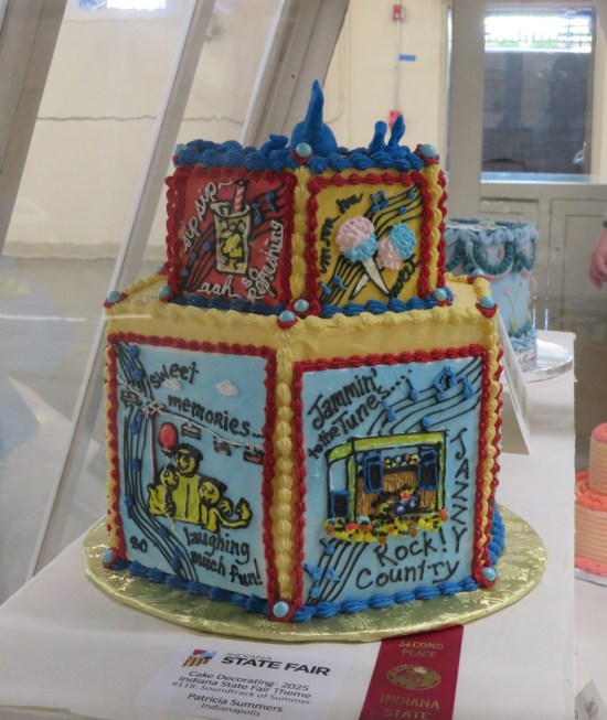 Two-tier hexagonal cake with pics of snacks and happy people listening to music.