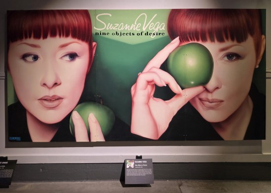 Two repainted closeups of Suzanne Vega in front of a green backdrop holding a green apple.