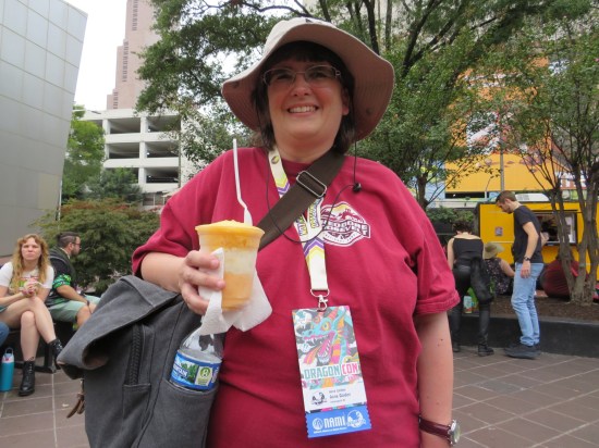 Anne with hat on, holding a frozen drink and smiling.