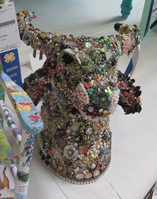 Bull head sculpture with every square centimeter covered in shiny objects.