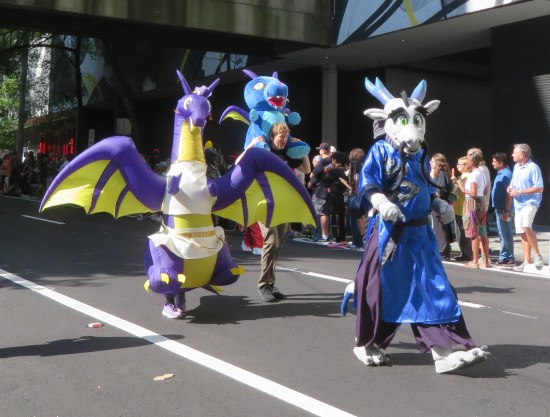 Three dragon costumes, including the iconic Dragon Con purple and yellow mascot.