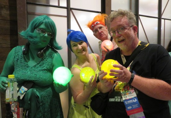 Three "Inside Out" cosplayers and me smiling and holding a glowing yellow ball of Joy.