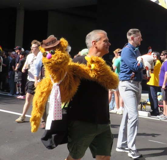 Fozzie Bear puppet with sunglasses, held in a parade.