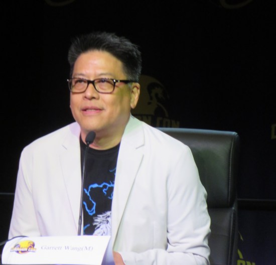 Garrett Wang in black glasses, white suit jacket and obscured black T-shirt.