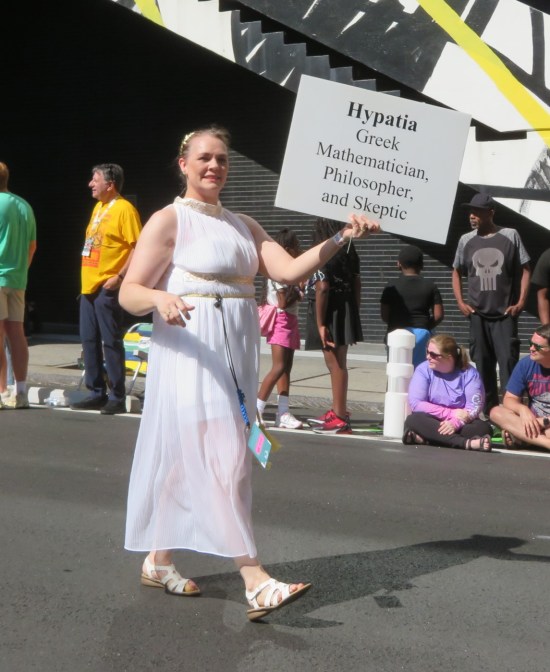 Hypatia cosplayer with sign reading "Hypatia: Greek mathematician, philosopher and skeptic."