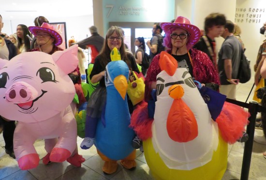 Three woman around our age, kindasorta dressed as cowgirls but each pretending to ride a giant inflatable pig, chicken with sunglasses, and some kind of bluish bird.