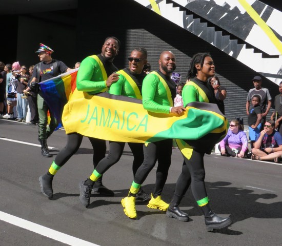 four cosplayers as a bobsledding team walking behind a Jamaica banner