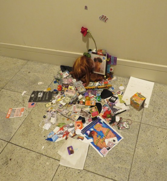 A bunch of trash thrown against a hotel wall, some of which has Jinu's face on it.