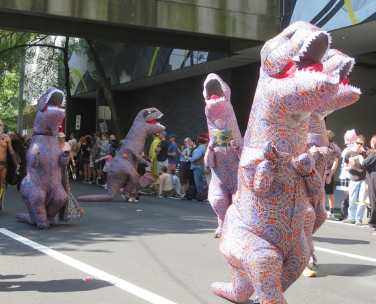 Parade of inflatable T-Rexes with skins made of the old Marriott Marquis carpet pattern.
