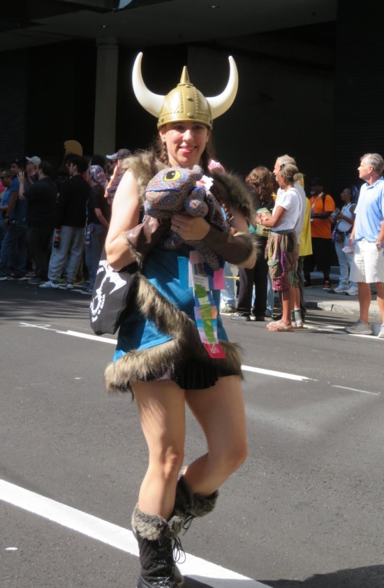 Viking woman cosplayer holding plush Toothless the dragon doll, hide covered in Marriott Marquis carpet pattern.