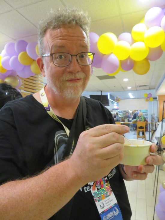me enjoying a small cup of veggie soup while waiting in line.