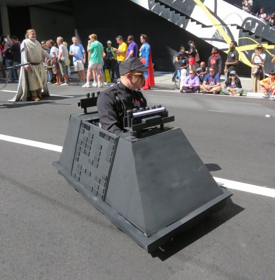 Imperial officer cosplayer driving around in a go-kart shaped like a Star Wars Mouse Droid.