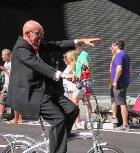 Mr. Six cosplayer riding and pointing, shot too closely to see much of his bike.