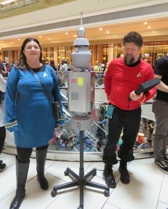 Homemade Nomad robot with two Trek fans in crew costumes, red and blue.