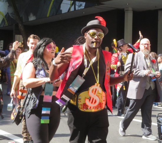 parade rapper with gold dollar sign necklace and black hat with red feather