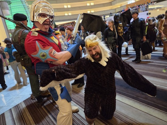Peacemaker and Eagly costumes in a giant hotel lobby.