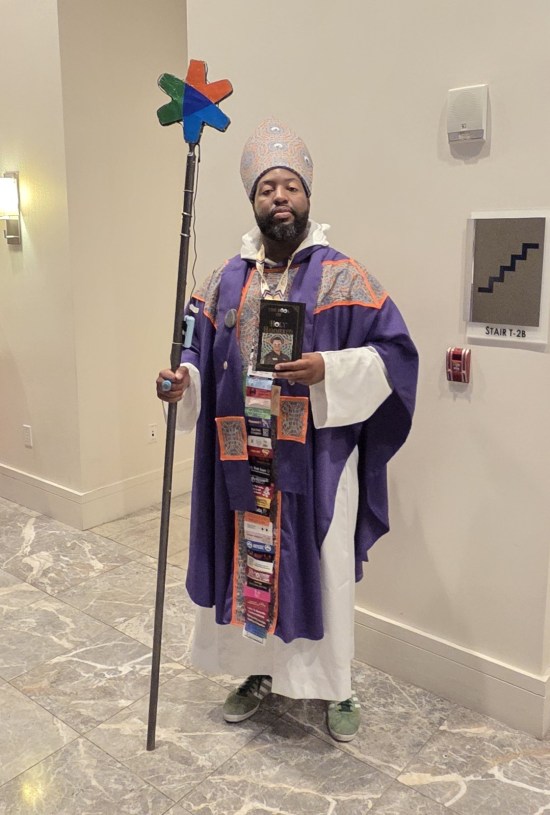 Guy in purple robe bearing the uniquely atrocious carpet pattern that once festooned the Marriott Marquis Atlanta. Guy holds staff and wears a mitre.