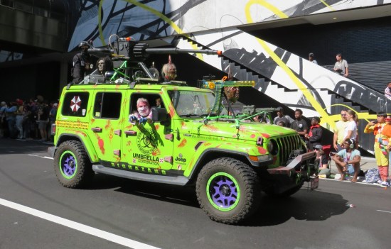 Resident Evil green jeep with passenger throwing hands toward us.