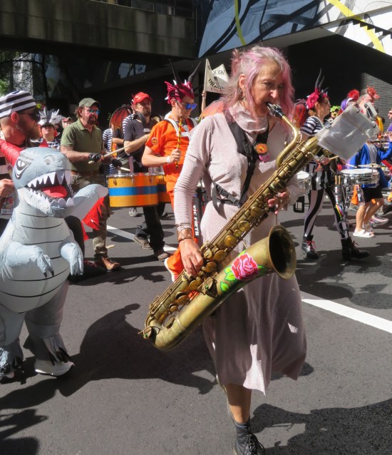 Lone saxophonist with a rose painted on the bell, followed by a guy in an inflatable raptor costume.
