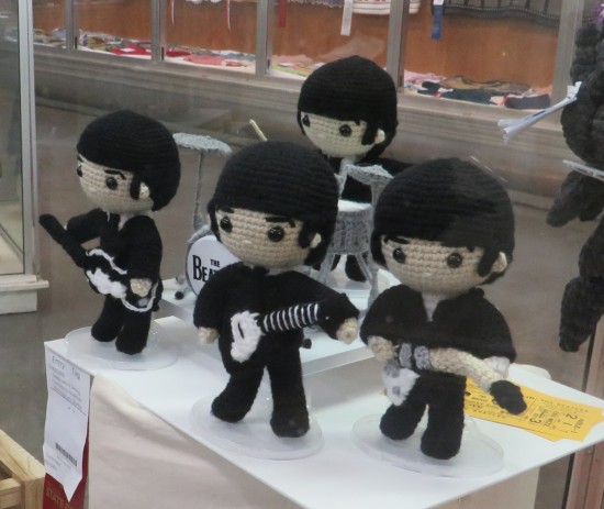 Knitted Beatles in concert in a a display case.